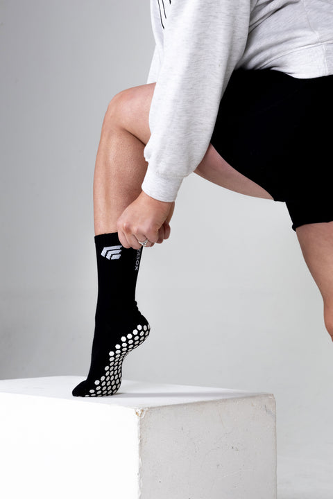 Person wearing black grip socks with white patterns on a light gray background