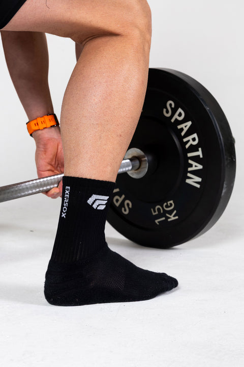 Person lifting a barbell wearing black grip socks.