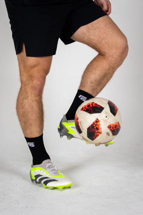 Person kicking a soccer ball with grip socks on